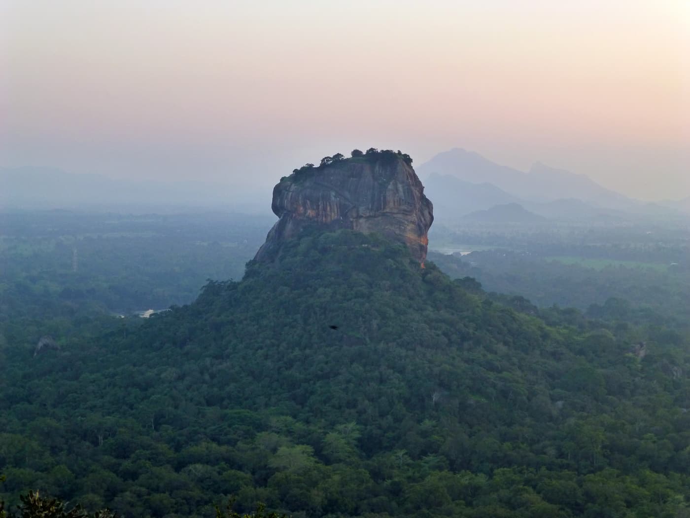 Sigiriya rock rising from the forest in hazy light, seen from the summit of Pidurangala